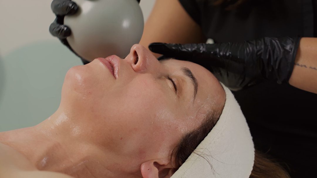 A client relaxing while a professional uses a rounded facial tool