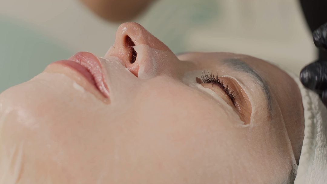 A hydrating mask being smoothed onto a client’s face